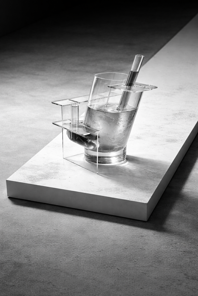 Cocktail glass containing the Walk Module cocktail and transparent structural elements shaped like deck chairs in the Liquid Translation of Catwalk Talk by VOLSER